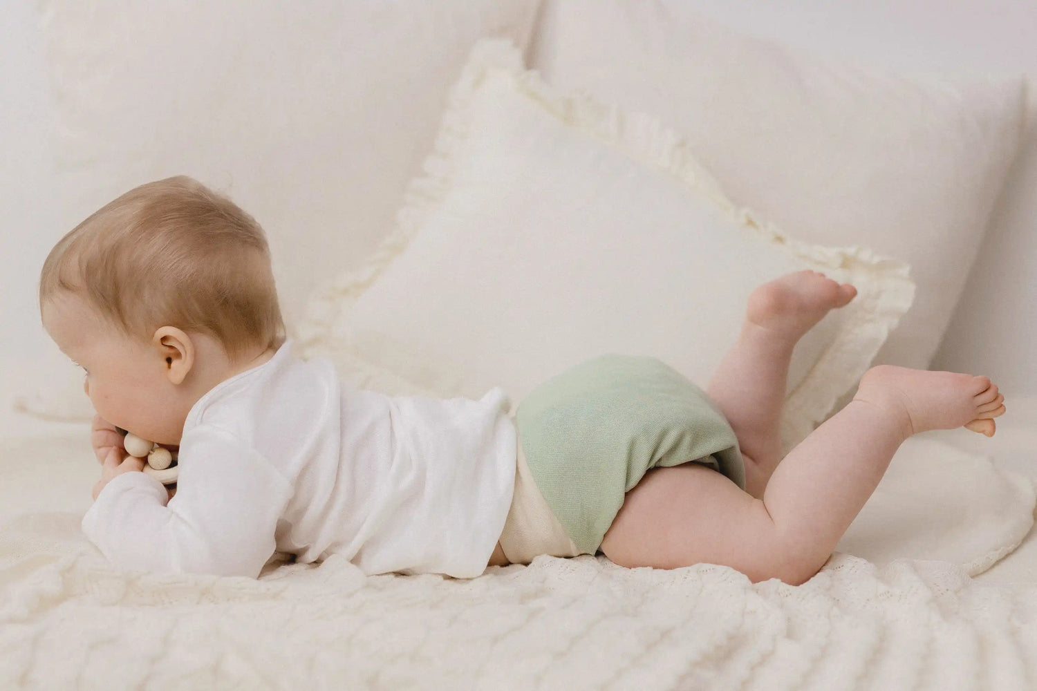 Baby liegt auf Bauch mit kniti an