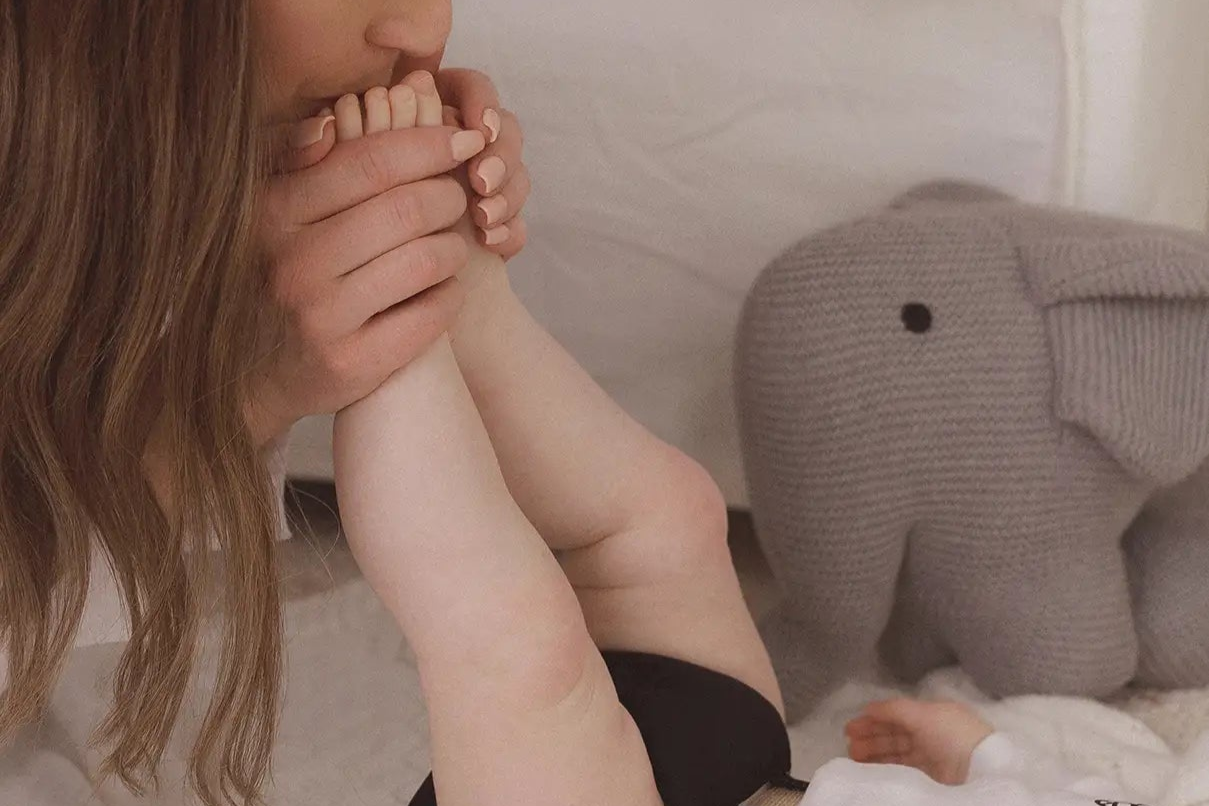 Frau küsst Baby auf den Fuß